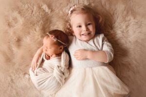 baby and big sister cuddled on fur blanket - boulder baby photographer