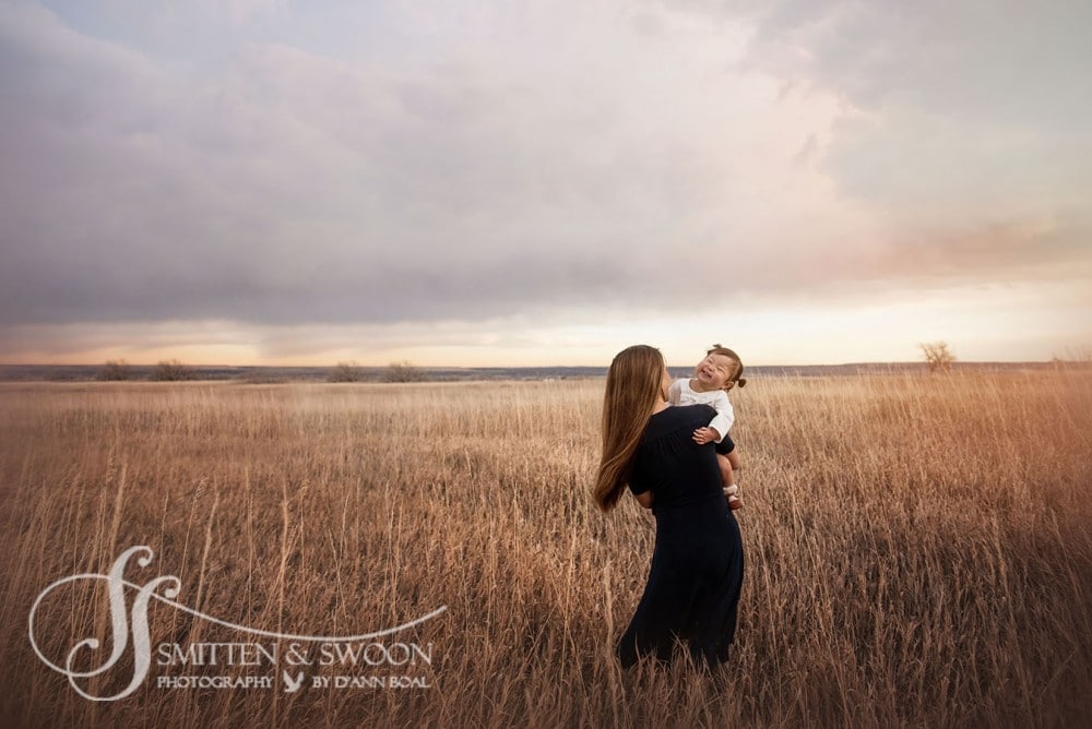 baby and mother walking through field at sunset