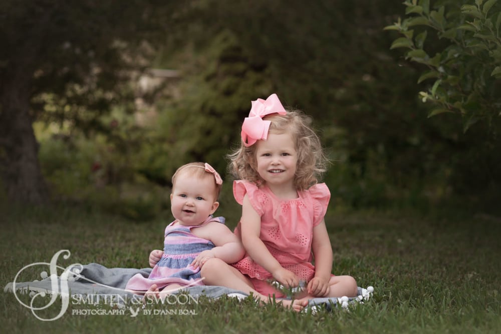 little sisters sitting together in garden {boulder baby photographer}