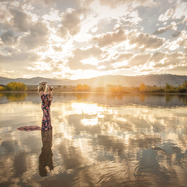 mother holding her baby girl standing in water at sunset - boulder photographer