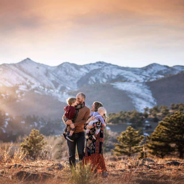love and light - boulder photographer family of four hugging in field at sunset