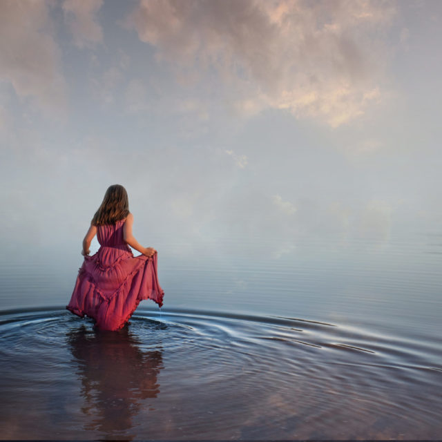 girl in pink dress walking into beautiful water that meets the sky - boulder photographer